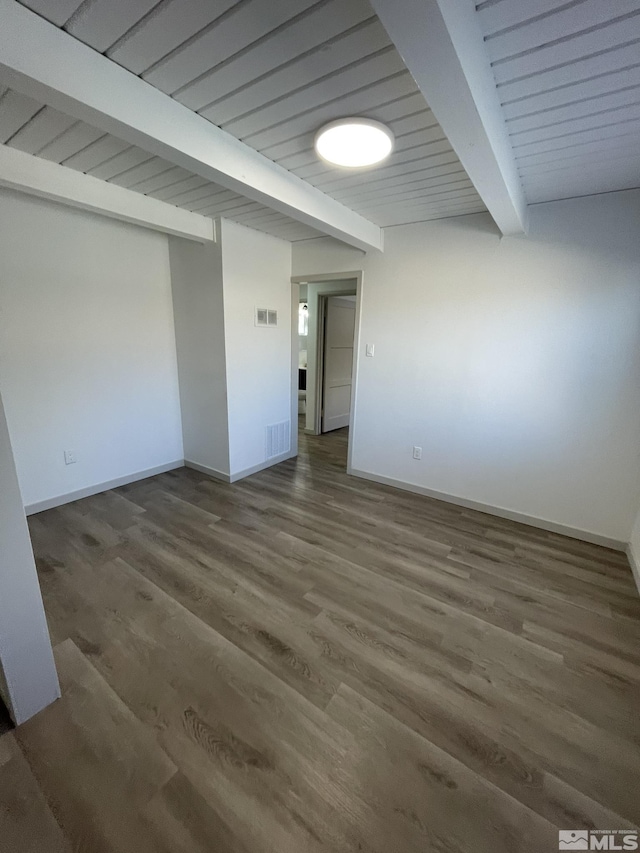 spare room featuring baseboards, visible vents, beam ceiling, and wood finished floors