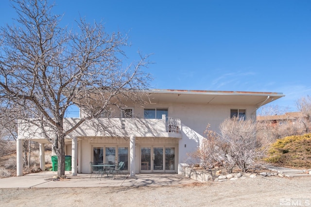 rear view of property featuring a balcony, a patio area, and stucco siding