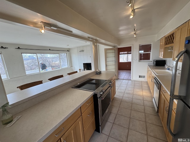 kitchen featuring light tile patterned floors, stainless steel appliances, a sink, visible vents, and light countertops