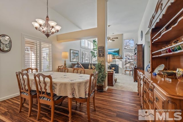 dining room featuring dark wood-style floors, a healthy amount of sunlight, baseboards, and ceiling fan with notable chandelier