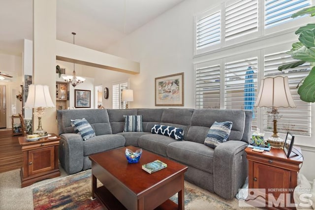 living area with plenty of natural light, a towering ceiling, and a notable chandelier