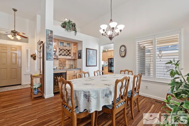 dining room with wine cooler, lofted ceiling, a bar, wood finished floors, and baseboards