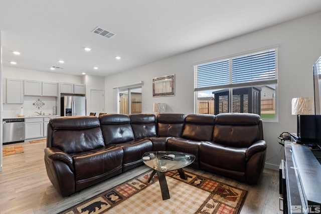 living area with light wood finished floors, visible vents, and recessed lighting