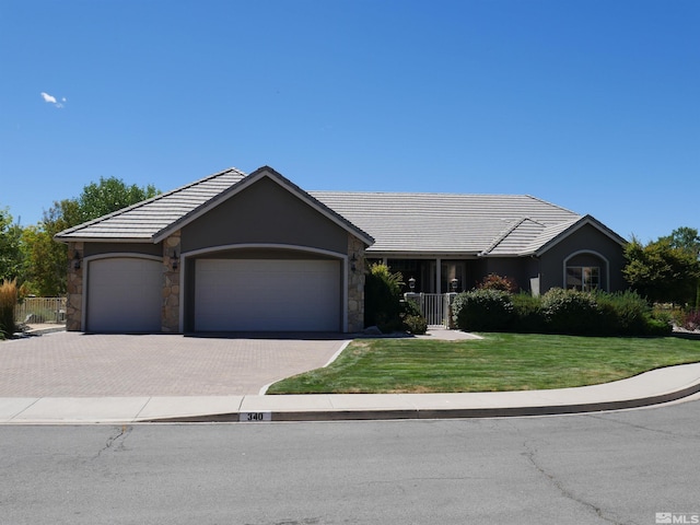 ranch-style house featuring a garage, a front lawn, decorative driveway, and a tile roof