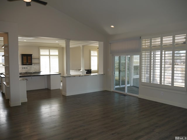 unfurnished living room with a ceiling fan, dark wood finished floors, vaulted ceiling, and ornate columns