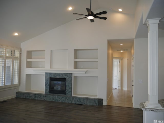 unfurnished living room with built in shelves, visible vents, a high end fireplace, wood finished floors, and ornate columns