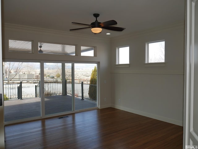 empty room with baseboards, visible vents, ceiling fan, ornamental molding, and wood finished floors