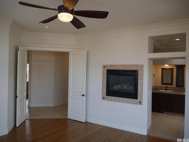 unfurnished living room featuring wood-type flooring, a sink, and crown molding