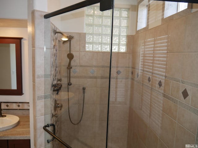 bathroom with tiled shower and vanity