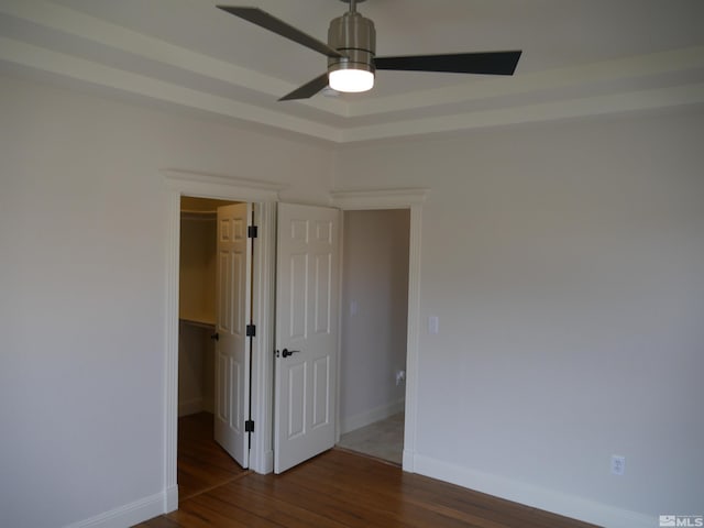 unfurnished bedroom with baseboards, ceiling fan, hardwood / wood-style floors, a spacious closet, and a closet