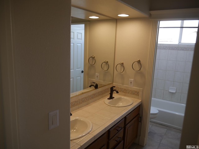 full bathroom featuring double vanity, a sink, and toilet