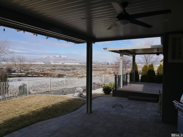 view of patio / terrace with fence, a mountain view, and a ceiling fan