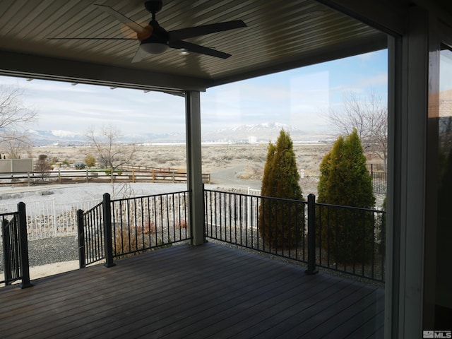 wooden terrace with ceiling fan, fence, and a mountain view