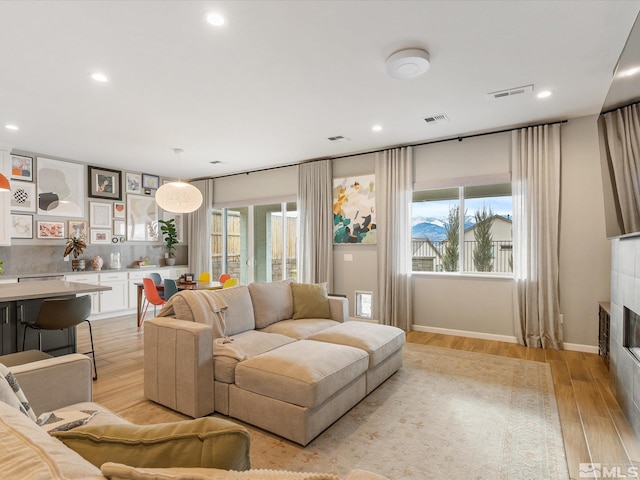 living area featuring light wood-style floors, a fireplace, and visible vents