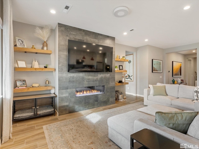 living area with a tile fireplace, recessed lighting, visible vents, baseboards, and wood tiled floor