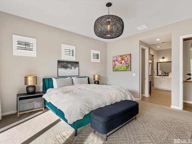 bedroom featuring visible vents, connected bathroom, light colored carpet, and baseboards