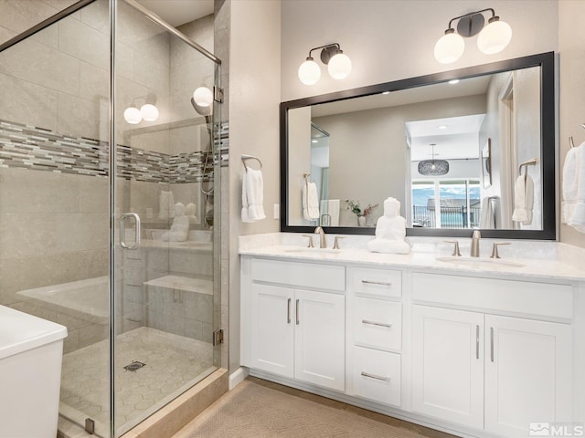 full bath with double vanity, a shower stall, and a sink