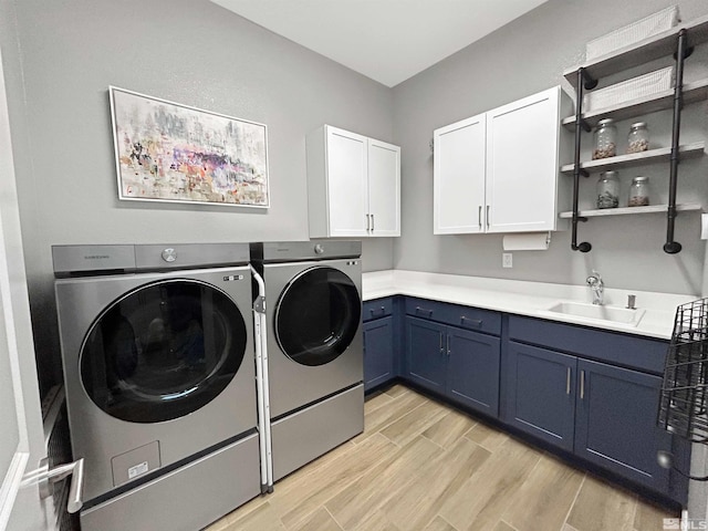 laundry room with light wood-style floors, cabinet space, a sink, and washer and clothes dryer