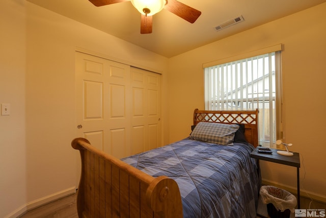 bedroom featuring baseboards, visible vents, a ceiling fan, wood finished floors, and a closet