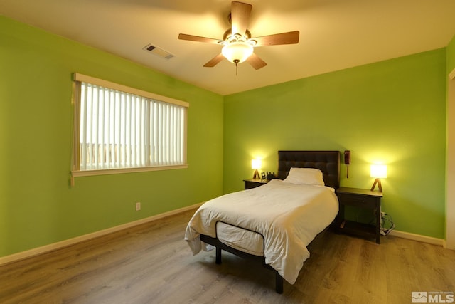 bedroom featuring a ceiling fan, baseboards, visible vents, and wood finished floors