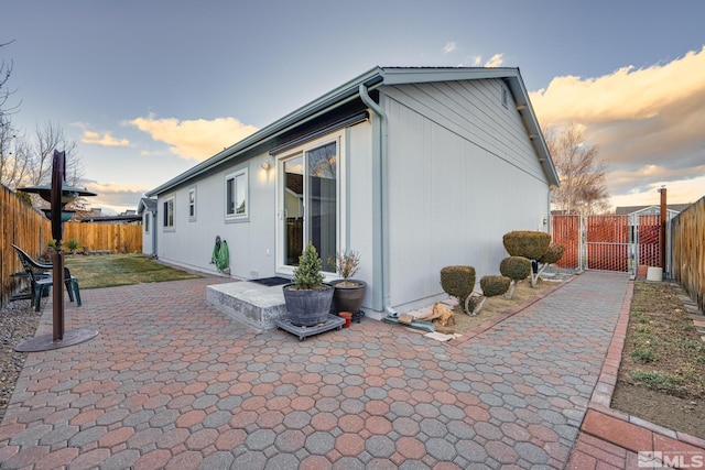 view of home's exterior with a fenced backyard, a gate, and a patio