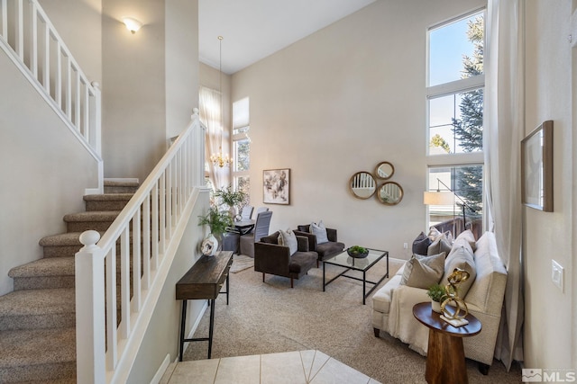 tiled living room with a chandelier, carpet flooring, a high ceiling, and stairs