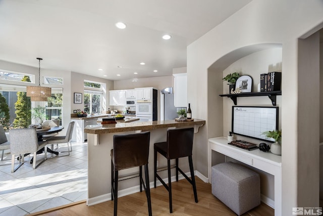 kitchen featuring white cabinets, appliances with stainless steel finishes, a breakfast bar, a peninsula, and recessed lighting