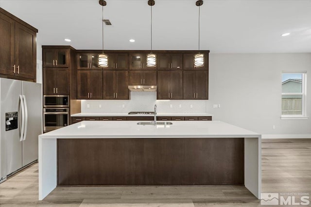 kitchen with appliances with stainless steel finishes, light countertops, a sink, and decorative backsplash