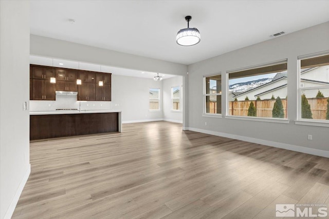 unfurnished living room with baseboards, visible vents, and light wood finished floors