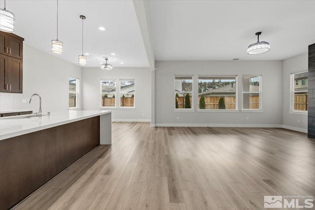 kitchen featuring open floor plan, light countertops, a sink, and light wood finished floors