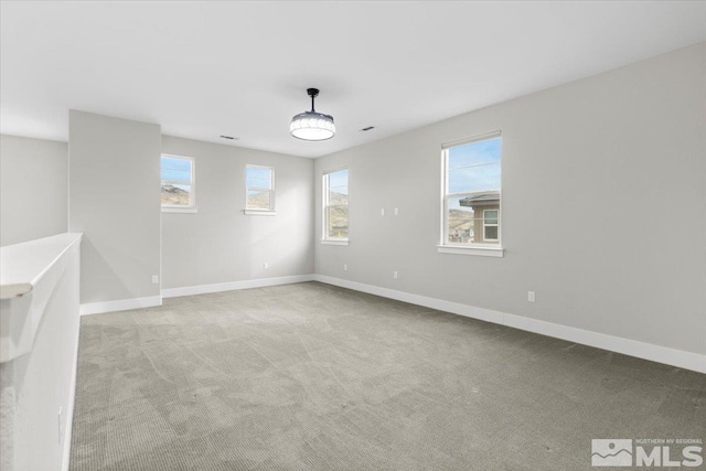 unfurnished room featuring light carpet and baseboards