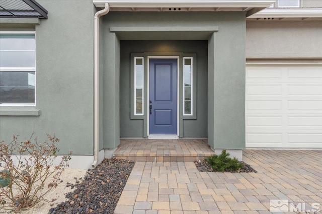 entrance to property with an attached garage and stucco siding