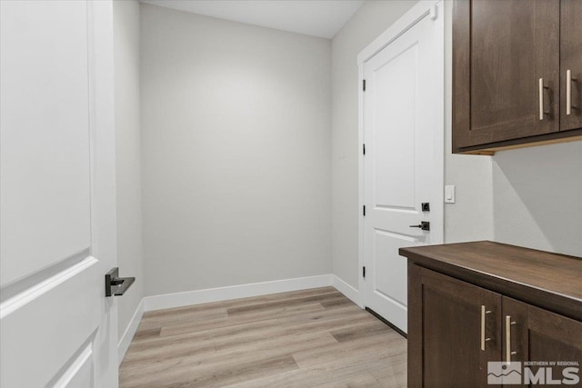 laundry area with light wood-style floors and baseboards