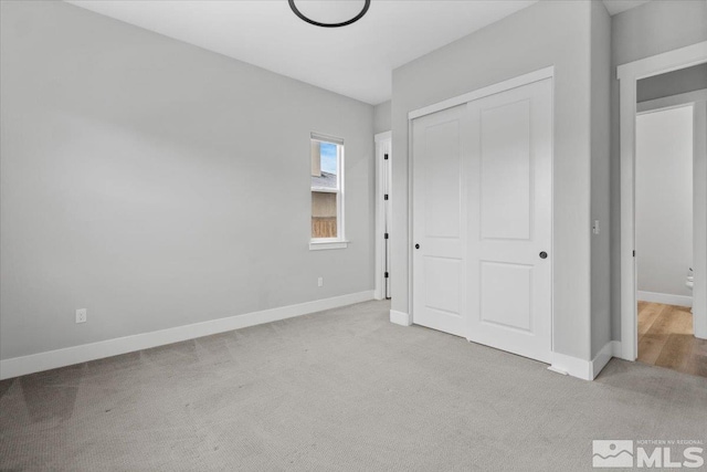 unfurnished bedroom with a closet, baseboards, and carpet flooring