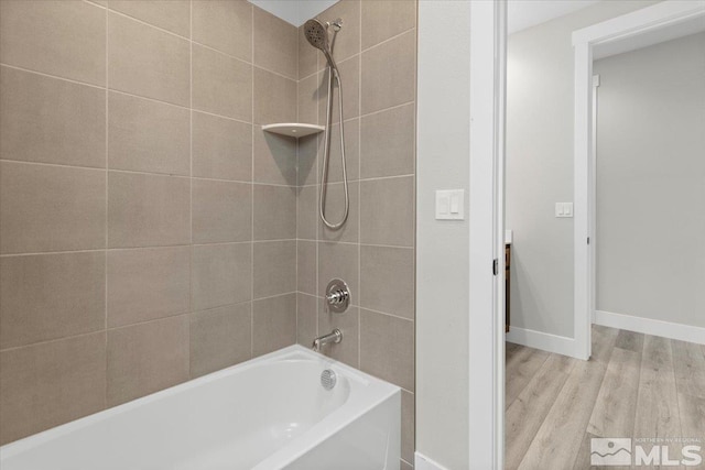 bathroom featuring  shower combination, wood finished floors, and baseboards