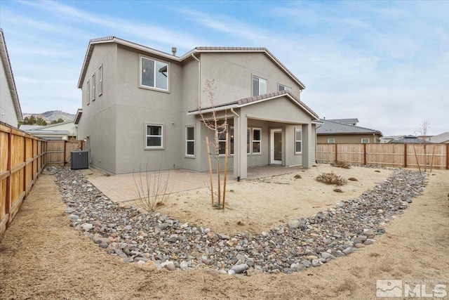 rear view of property with cooling unit, a fenced backyard, a patio, and stucco siding