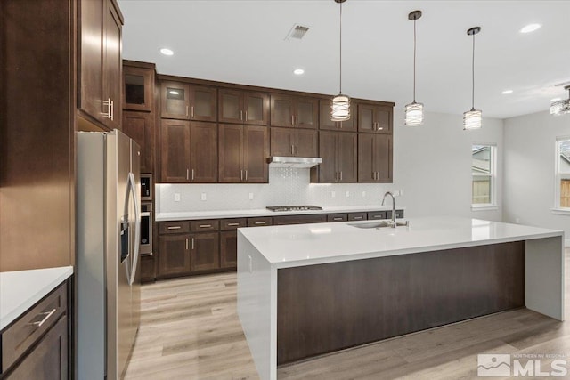 kitchen featuring light countertops, visible vents, appliances with stainless steel finishes, a sink, and under cabinet range hood