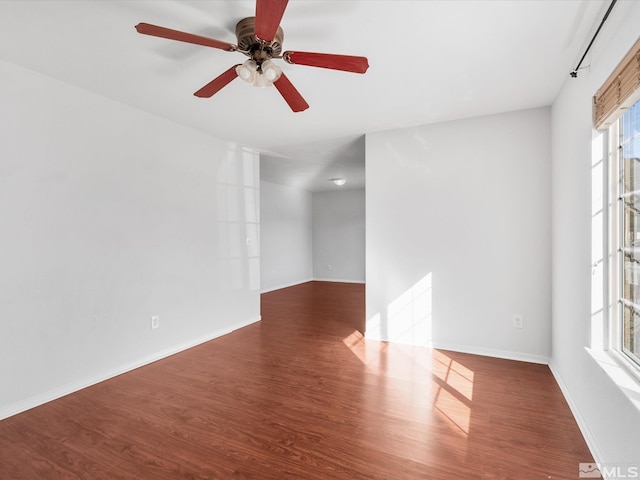 empty room featuring ceiling fan, wood finished floors, and baseboards