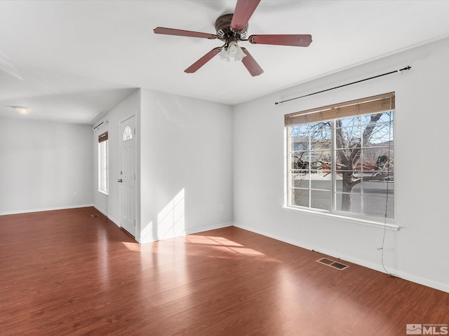 empty room featuring wood finished floors, visible vents, and baseboards