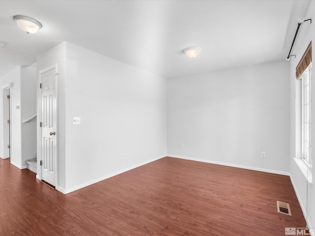 unfurnished room featuring dark wood-style floors, visible vents, and baseboards