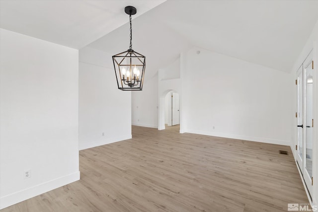 empty room featuring arched walkways, light wood finished floors, visible vents, a chandelier, and baseboards