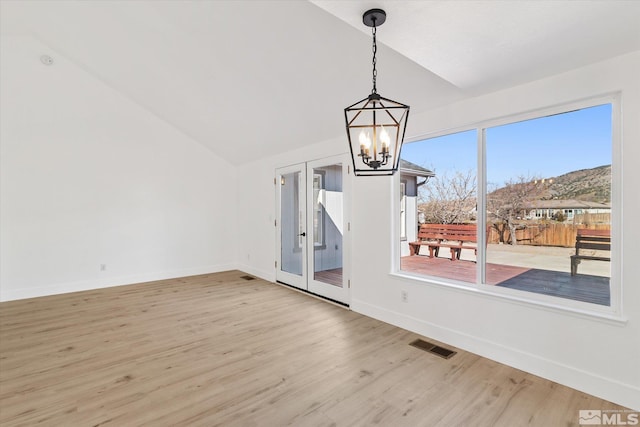 unfurnished dining area featuring light wood finished floors, visible vents, vaulted ceiling, and a chandelier