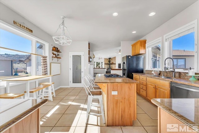 kitchen featuring light tile patterned floors, a kitchen island, a sink, stainless steel dishwasher, and freestanding refrigerator