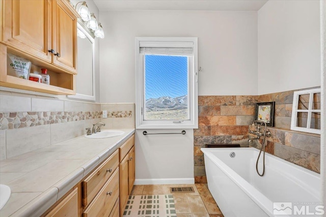 bathroom featuring a washtub, visible vents, vanity, tile patterned flooring, and baseboards