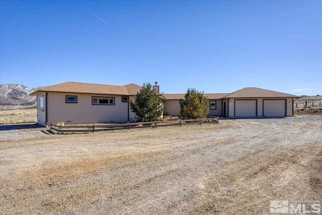 ranch-style house with a garage, driveway, a chimney, and a mountain view