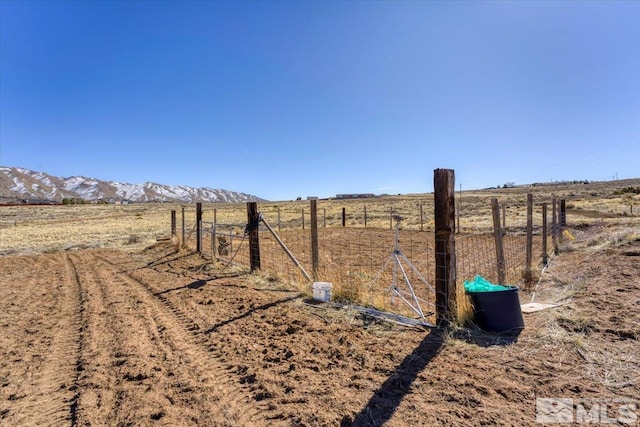 view of yard featuring a rural view, fence, and a mountain view