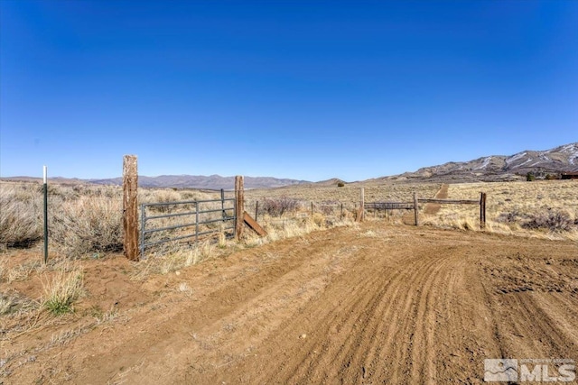 view of yard with a rural view, fence, and a mountain view