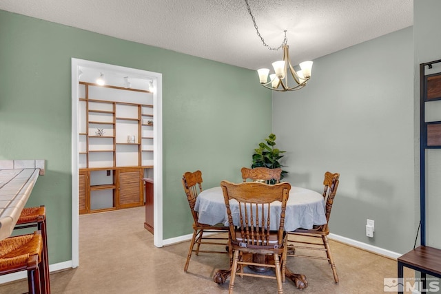 dining space featuring an inviting chandelier, baseboards, a textured ceiling, and carpet flooring