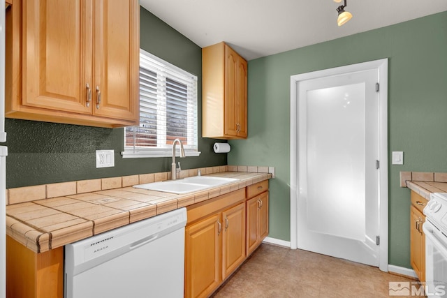 kitchen featuring white appliances, tile counters, baseboards, and a sink