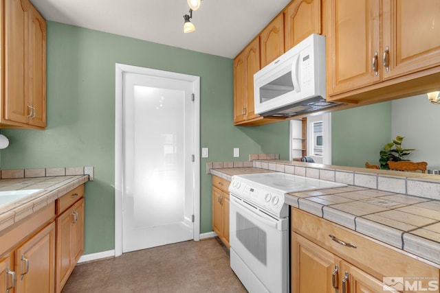 kitchen featuring white appliances, baseboards, and tile counters